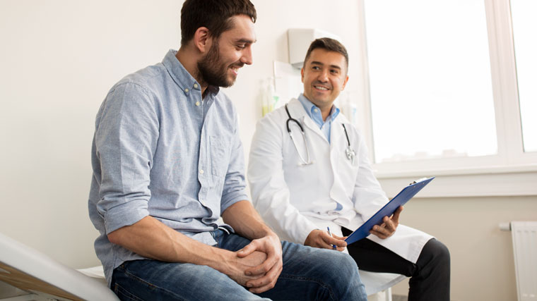 A family doctor and male patient smile at each other as they discuss his health