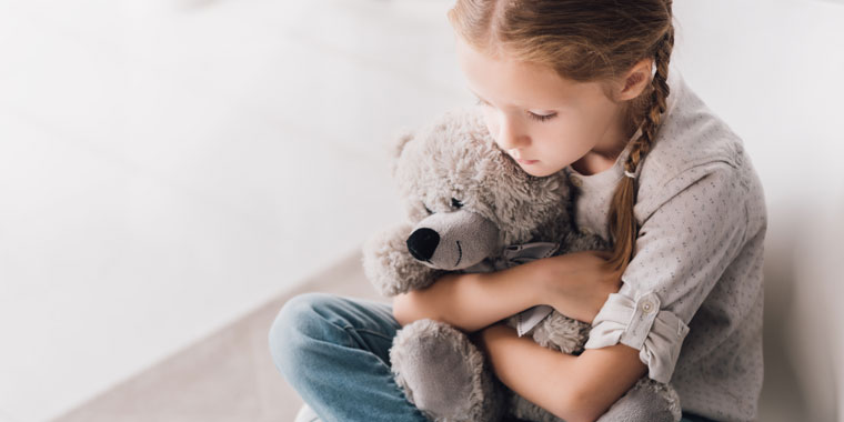 Child hugs a stuffed bear as she deals with feelings of anxiety